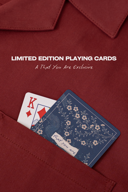 Two playing cards, one red and one blue with floral design, in a red shirt pocket.
